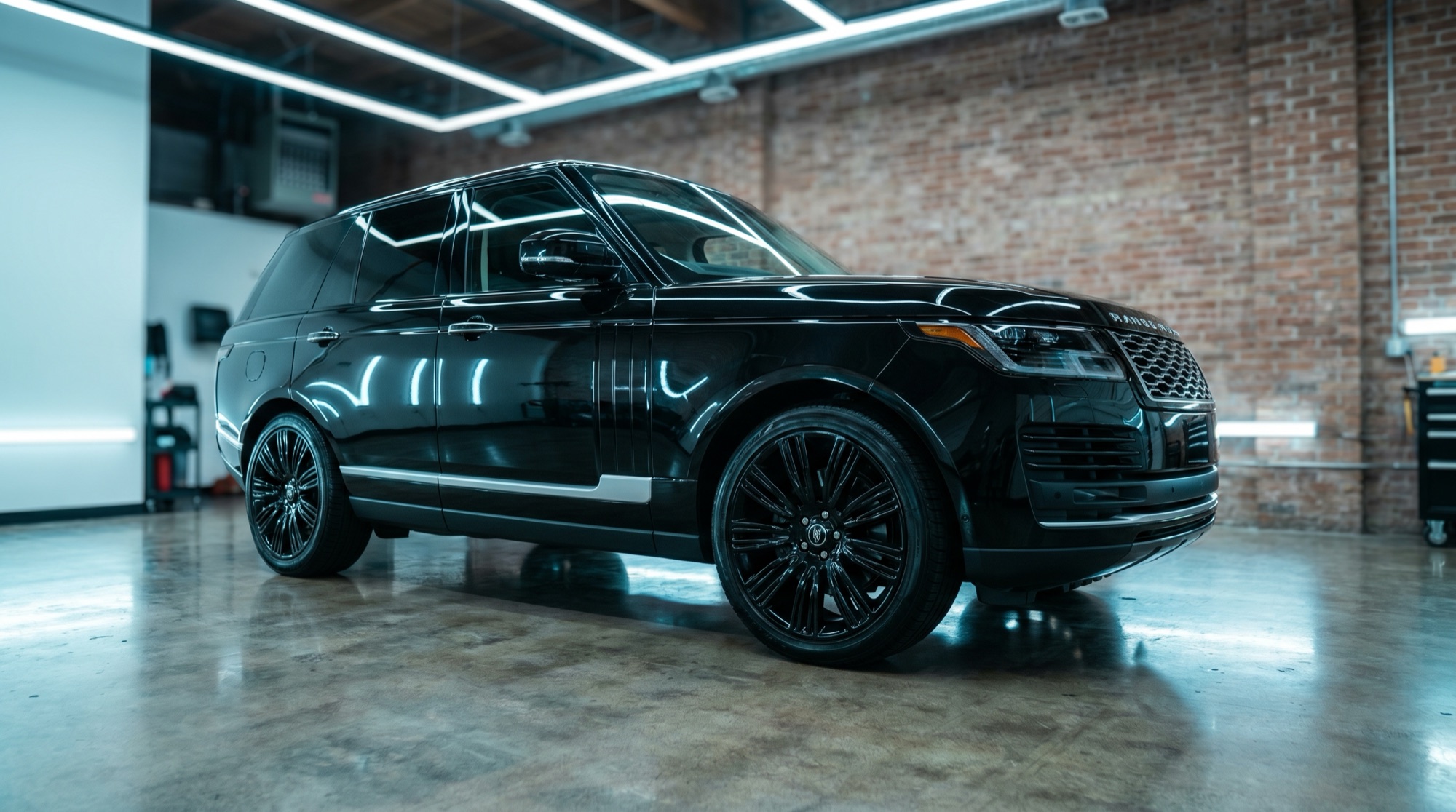 Fully detailed black luxury SUV gleaming under studio light bars